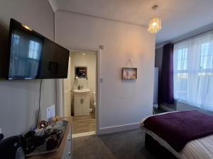 a bedroom with a bed and a flat screen tv at Westbrook Lodge Guest House in Margate