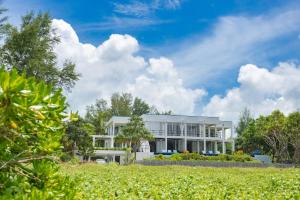 ein weißes Gebäude mit Bäumen davor in der Unterkunft Black Pearl 8 Bedroom Beach Villa Private Pool Gym Free Car Free Water and Electricity Maid 10 Meters to the Beach in Ban Bo Sai Klang