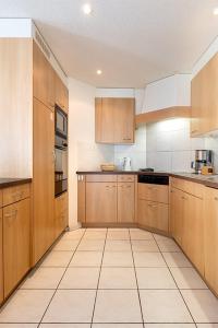 a kitchen with wooden cabinets and a tile floor at Annika Apartment in Andermatt