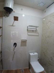 a bathroom with a toilet and a white wall at The Millennium Kashi Hotel in Varanasi