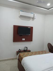 a bedroom with a bed and a tv on the wall at The Millennium Kashi Hotel in Varanasi