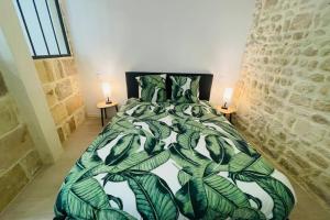 ein Schlafzimmer mit einem Bett mit einer grünen, grünen Tagesdecke in der Unterkunft Le Valentin in Saint-Jean-dʼAngély