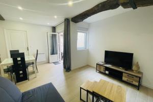 ein Wohnzimmer mit Fernseher und Tisch in der Unterkunft Le Valentin in Saint-Jean-dʼAngély + 9 Fotos
