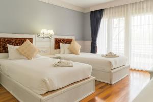 two beds in a bedroom with white walls and wood floors at River Breeze Chiangsaen in Chiang Saen