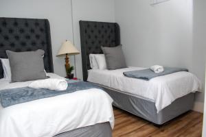 2 camas en una habitación con blanco y gris en Twilight Self Catering, en Windhoek