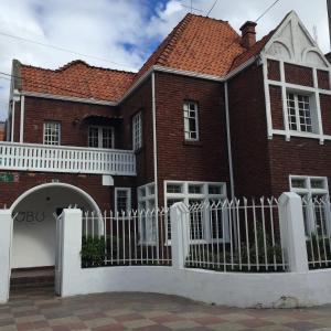 a red brick house with a white fence at Hobu Hostel in Bogotá