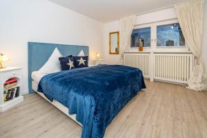 a bedroom with a large bed with a blue blanket at Altstadttor 17 in Westerland