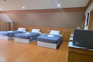 two beds in a room with a flat screen tv at River Breeze Chiangsaen in Chiang Saen