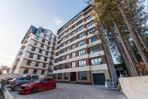 ein rotes Auto, das vor einem Gebäude geparkt ist in der Unterkunft Apartmani Gomax 3,4 & SPA Zlatibor in Zlatibor