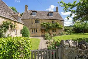 an old stone house with a fence in front of it at Orchard Cottage - Beautiful Home near Broadway! in Weston Subedge