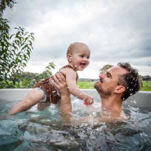 a man holding a baby in the water at Slow Living bij Mölke x Wellnesslodges in Zuna