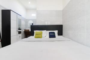 a bedroom with a white bed with two yellow pillows at Urbanview Ava Guest House Goa Gong in Jimbaran +22 photos
