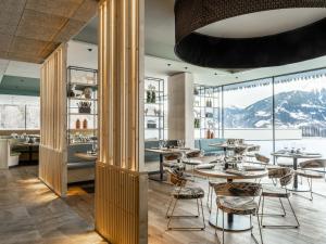 施伦斯Falkensteiner Family Hotel Montafon - The Leading Hotels of the World的餐厅配有桌椅,位于山脉的背景中。 更多34张照片