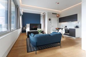 a living room with a blue couch and a kitchen at Penthouse-Flair with Skyline-View in Vienna