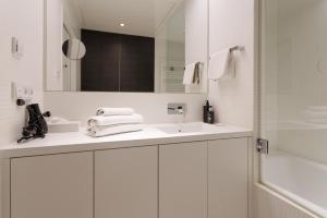 a white bathroom with a sink and a mirror at Penthouse-Flair with Skyline-View in Vienna