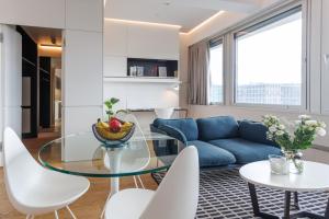 a living room with a blue couch and a glass table at Penthouse-Flair with Skyline-View in Vienna +31 photos