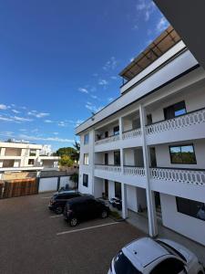 a white building with cars parked in a parking lot at Casa Nampala Diani in Ukunda