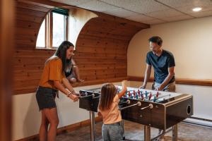 a woman and a man and a little girl playing chess at Chalet Alpin Walk to Lake and Beach with Spa and BBQ in Huberdeau