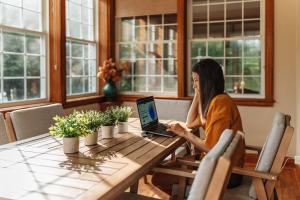 a woman sitting at a table using a laptop computer at Chalet Alpin Walk to Lake and Beach with Spa and BBQ in Huberdeau +83 photos