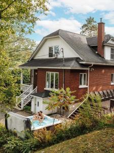 a man in a bath tub in front of a house at Chalet Alpin Walk to Lake and Beach with Spa and BBQ in Huberdeau