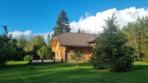 a log cabin in a yard with a green lawn at Purgaiļi in Smiltene