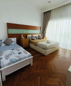 two beds in a bedroom with wooden floors at Marina Chic l Stylish 2BR Retreat l Straits Quay in Tanjung Bungah