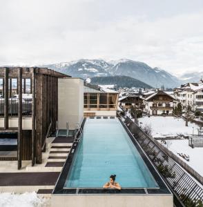 una donna che nuota in una piscina in cima a un edificio di Falkensteiner Hotel Kronplatz - The Leading Hotels of the World a Brunico
