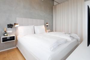 a white bedroom with a large white bed with white pillows at Exklusives Skyline-View Loft - Nähe Zentrum Wien in Vienna