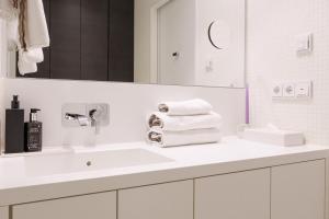 a white bathroom with a sink and a mirror at Exklusives Skyline-View Loft - Nähe Zentrum Wien in Vienna