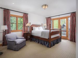 a bedroom with a bed and a chair and windows at RMR: Granite Ridge Lodge 3217 in Teton Village in Teton Village