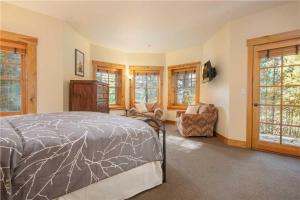 a bedroom with a bed and a chair and windows at RMR: Granite Ridge Cabin 7586 in Teton Village in Teton Village