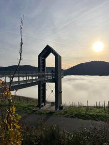 Un puente sobre un cuerpo de agua con el sol al fondo. en Schendels Suite, en Bernkastel-Kues 6 fotos más