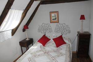 ein Schlafzimmer mit einem Bett mit zwei roten Kissen in der Unterkunft Les Vieilles Treilles in Noailhac
