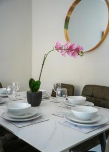 a white table with plates and glasses and a mirror at Stobhill Apartment in Glasgow
