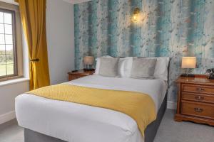 een slaapkamer met een groot bed met een gele deken bij Cricklade House Hotel, Sure Hotel Collection by Best Western in Cricklade