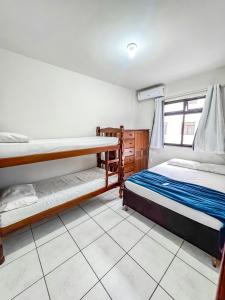 a bedroom with two bunk beds and a tiled floor at Hospedatom - Apartamento Economy Prainha Arraial do Cabo in Arraial do Cabo