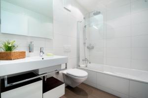 a white bathroom with a sink and a toilet at RIVER Apartment in Andermatt +17 photos