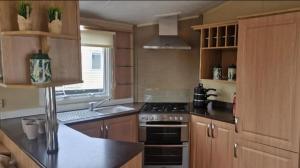 Una cocina con gabinetes de madera y un horno de estufa. en Lovely 8 Berth Caravan With Large Decking At Withernsea Sands Ref 79005Kg, en Waxholme 5 fotos más