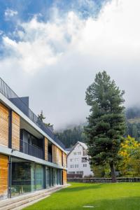 a view of a building with a tree in the foreground at RIVER Apartment in Andermatt