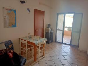 a room with a table and a kitchen with a microwave at Da Nanni in Villasimius