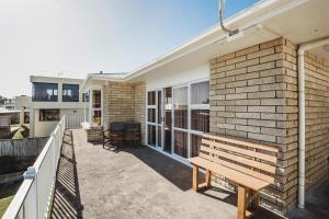 a wooden bench on the balcony of a house at Beach House On Hamblyn in New Plymouth