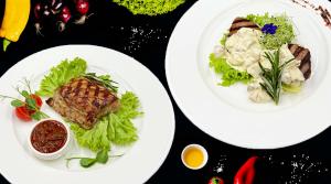two plates of food with meat and salad on a table at Дизайн-готель ROAD in Kyiv