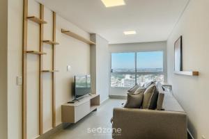 uma sala de estar com um sofá e uma TV em Aptos em Prédio com Piscina e Academia - GRL em Anápolis