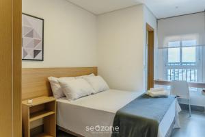 um pequeno quarto com uma cama e uma janela em Aptos em Prédio com Piscina e Academia - GRL em Anápolis