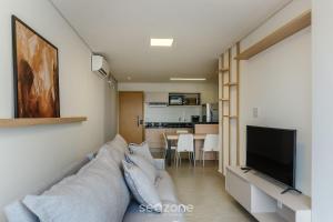 uma sala de estar com um sofá e uma TV de tela plana em Aptos em Prédio com Piscina e Academia - GRL em Anápolis mais 5 fotografias