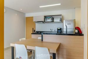 uma cozinha com uma mesa de madeira e cadeiras brancas em Aptos em Prédio com Piscina e Academia - GRL em Anápolis