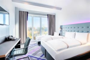 una habitación de hotel con dos camas y un escritorio en Premier Inn Lübeck City Stadtgraben, en Lübeck 11 fotos más