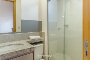 um banheiro com box de vidro e pia em Aptos em Prédio com Piscina e Academia - GRL em Anápolis