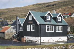 una casa en blanco y negro con techo verde en Toftarstova - Seaview - Historic - 3BR House, en Kvívík