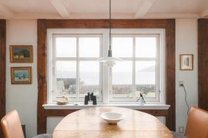 Un comedor con una mesa y un gran ventanal. en Toftarstova - Seaview - Historic - 3BR House, en Kvívík